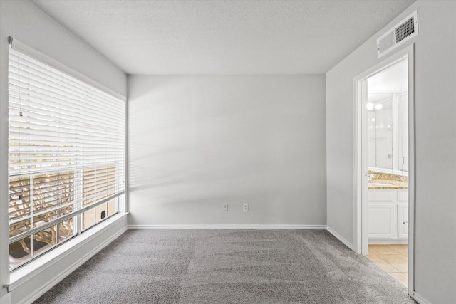 unfurnished room with a healthy amount of sunlight, visible vents, and light colored carpet