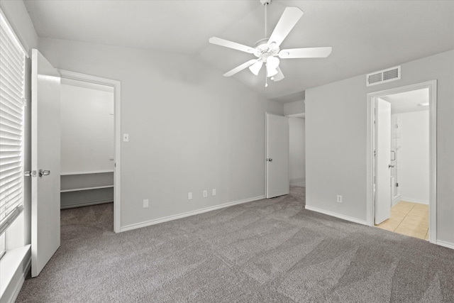 unfurnished bedroom featuring light colored carpet, visible vents, a ceiling fan, vaulted ceiling, and baseboards