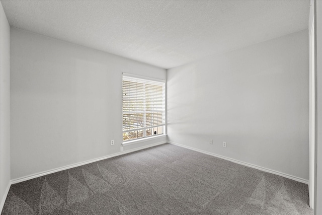 empty room featuring a textured ceiling, carpet flooring, and baseboards