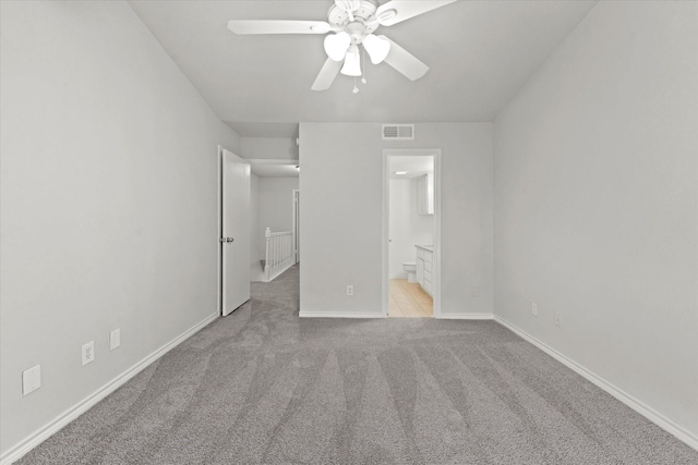 unfurnished bedroom featuring baseboards, visible vents, connected bathroom, light colored carpet, and ceiling fan