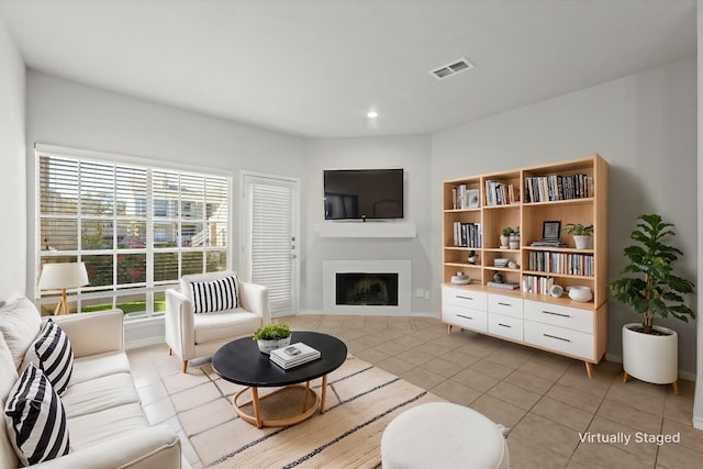 living area with light tile patterned floors, baseboards, visible vents, a fireplace, and recessed lighting