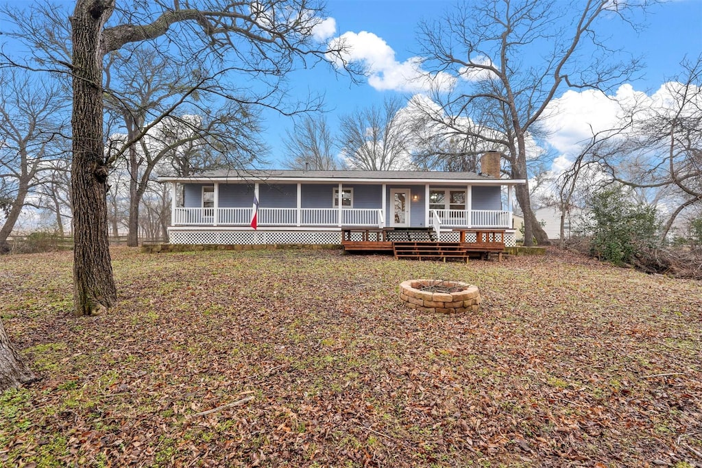 view of front of house with a porch, an outdoor fire pit, and a chimney