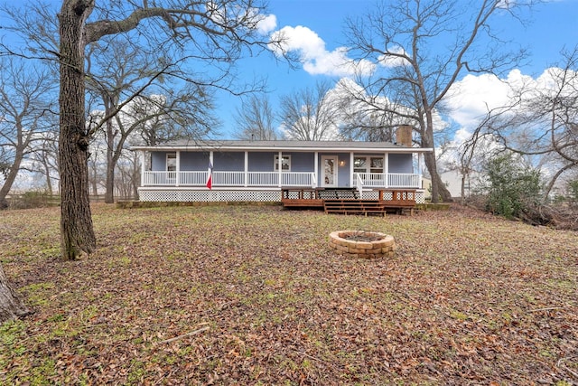 view of front of house with a porch, an outdoor fire pit, and a chimney