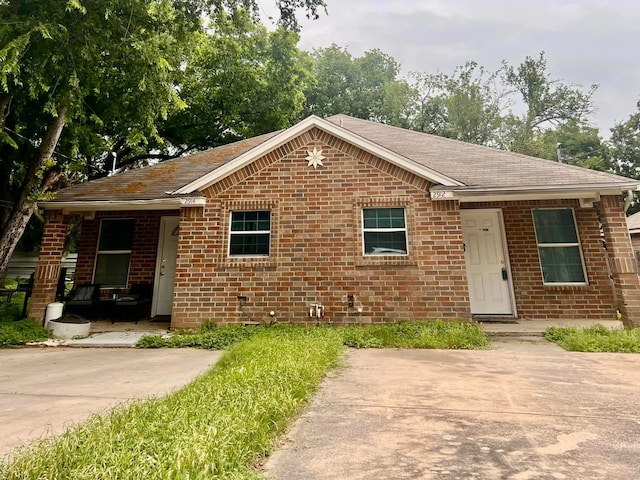 view of front of house with roof with shingles and brick siding