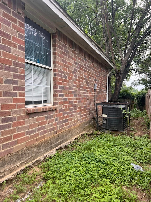 view of home's exterior with brick siding, fence, and central AC