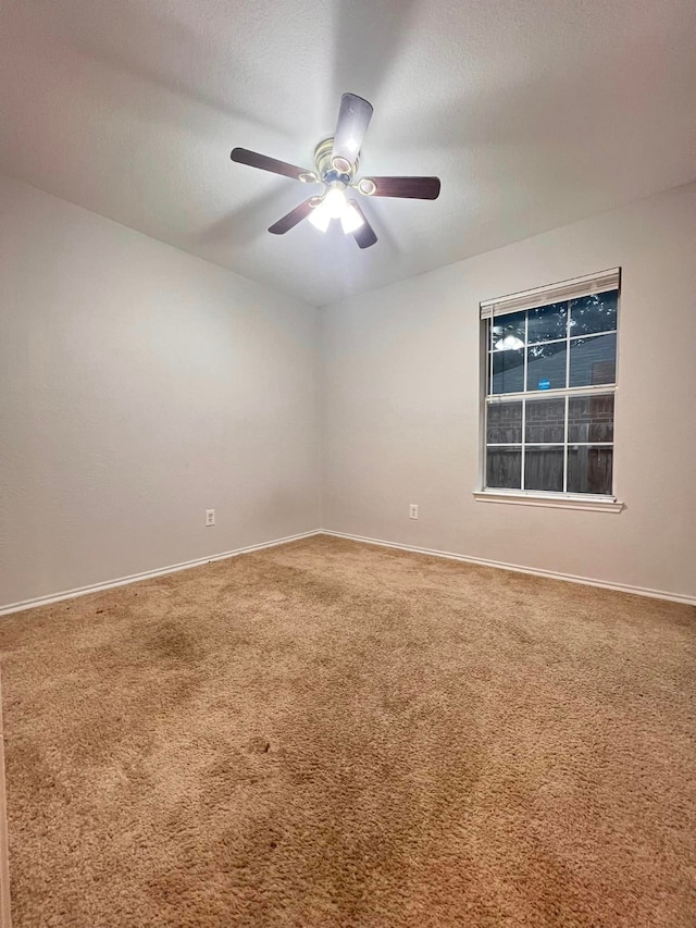 spare room with carpet floors, a textured ceiling, baseboards, and a ceiling fan