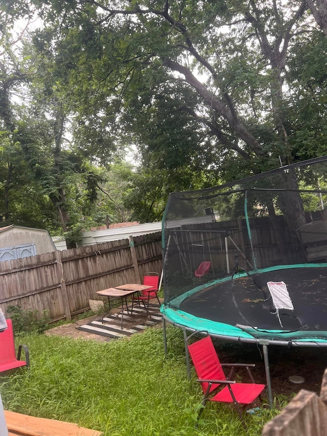 view of yard with a trampoline and a fenced backyard