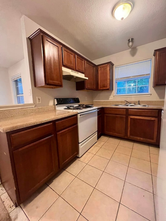 kitchen featuring light tile patterned floors, under cabinet range hood, a sink, electric stove, and light countertops