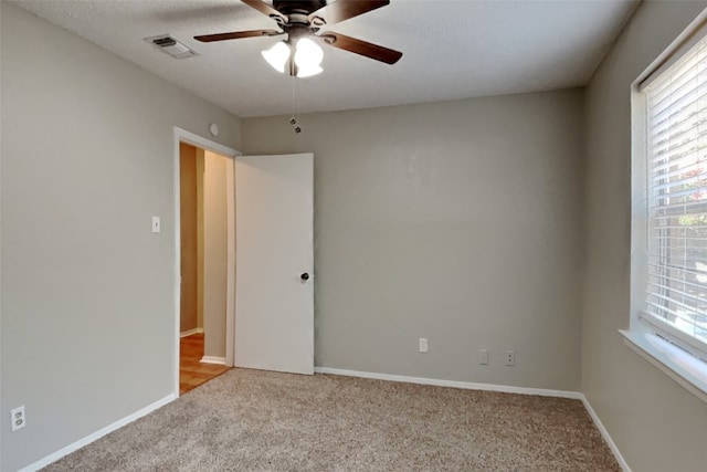 empty room featuring light carpet, plenty of natural light, and visible vents