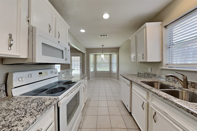 kitchen with white appliances, white cabinets, a sink, and hanging light fixtures