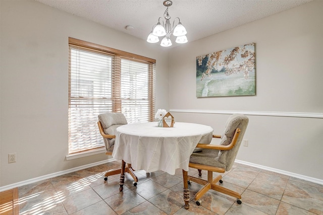 dining area featuring tile patterned flooring, a notable chandelier, a textured ceiling, and baseboards