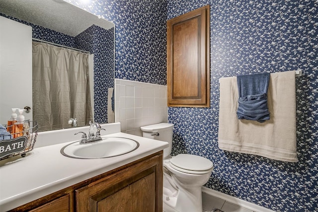 bathroom featuring toilet, wallpapered walls, and vanity