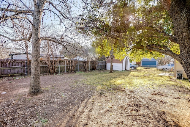 view of yard featuring a shed, a fenced backyard, and an outbuilding