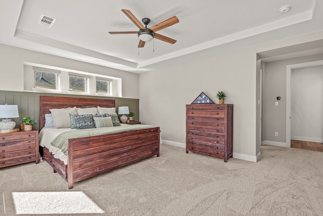 carpeted bedroom with a tray ceiling, visible vents, ceiling fan, and baseboards