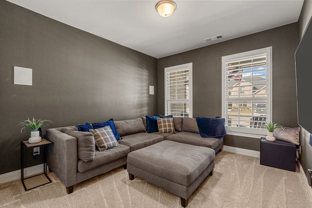 living area with light colored carpet, visible vents, and baseboards