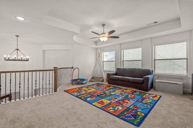 recreation room with a tray ceiling, carpet flooring, visible vents, and ceiling fan with notable chandelier