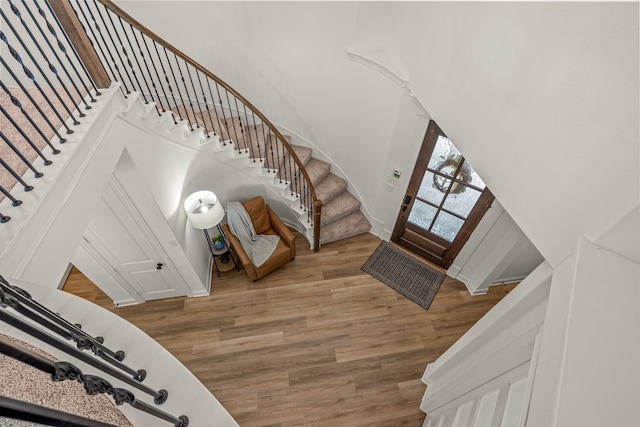 entryway with wood finished floors, a towering ceiling, baseboards, and stairs