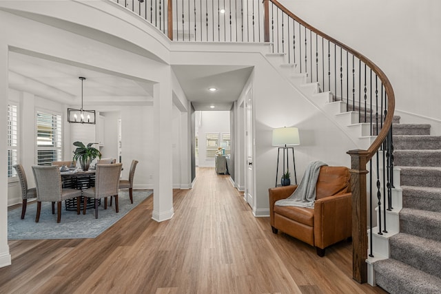 entrance foyer with a notable chandelier, a high ceiling, wood finished floors, baseboards, and stairs