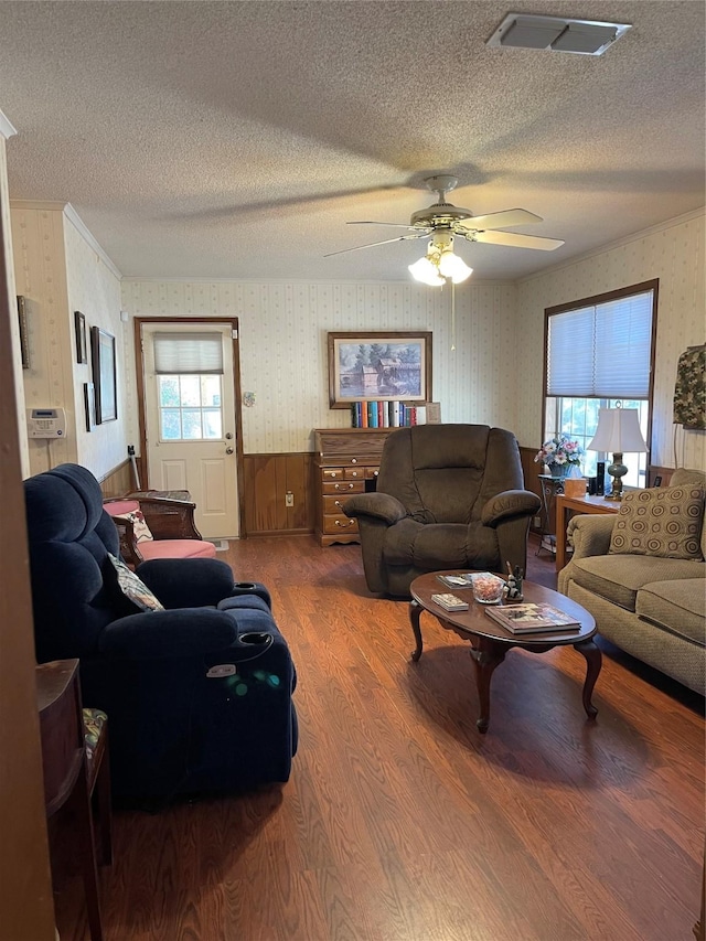 living area with wood finished floors, visible vents, a textured ceiling, and wallpapered walls