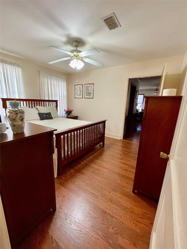 bedroom with visible vents, baseboards, and wood finished floors