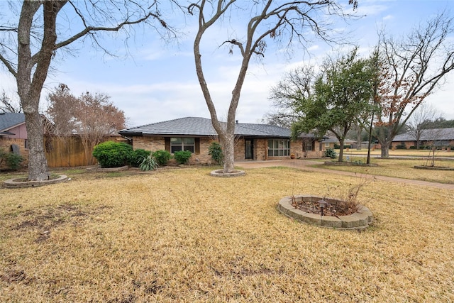 view of front of house featuring a front yard, brick siding, and fence