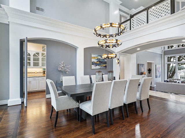 dining room featuring dark wood-style floors, a high ceiling, visible vents, and a chandelier