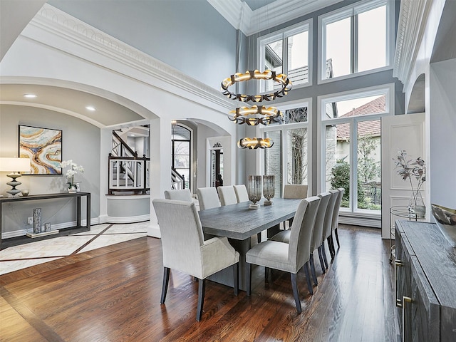 dining area with stairs, ornamental molding, wood finished floors, and a high ceiling