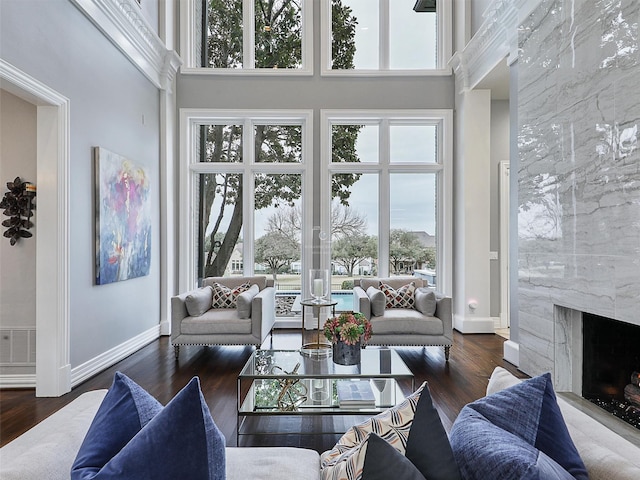 living room with baseboards, a premium fireplace, visible vents, and wood finished floors