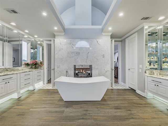 full bath with ornamental molding, visible vents, a fireplace, and wood finished floors