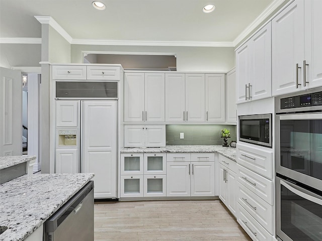 kitchen featuring tasteful backsplash, white cabinets, built in appliances, crown molding, and light wood-style floors