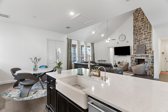 kitchen with light stone counters, dark wood-style floors, a fireplace, visible vents, and open floor plan