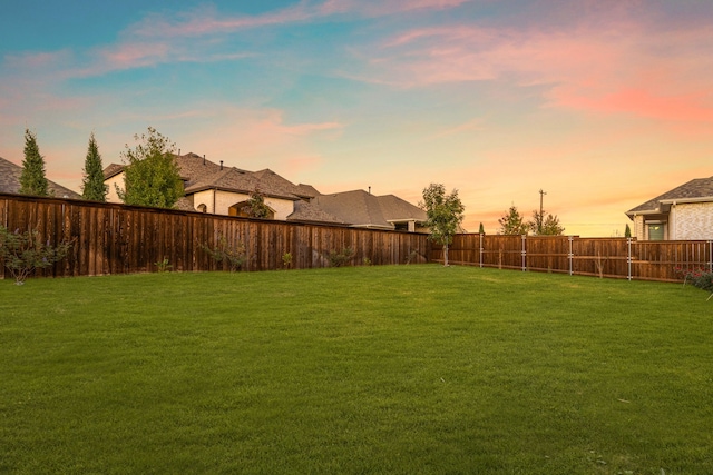 yard at dusk featuring a fenced backyard