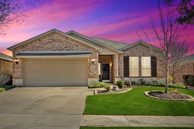 single story home with an attached garage, brick siding, driveway, a lawn, and roof with shingles