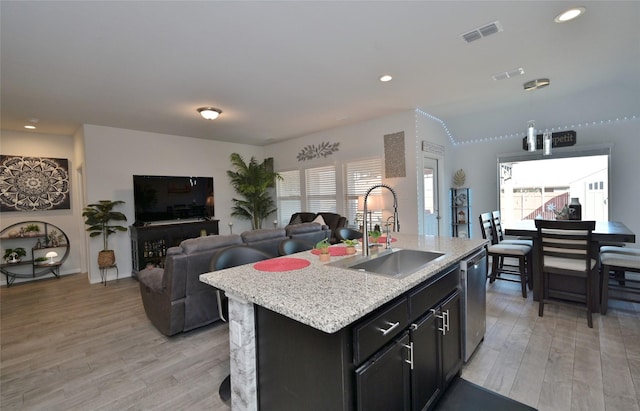 kitchen featuring a sink, visible vents, open floor plan, light wood-type flooring, and dishwasher