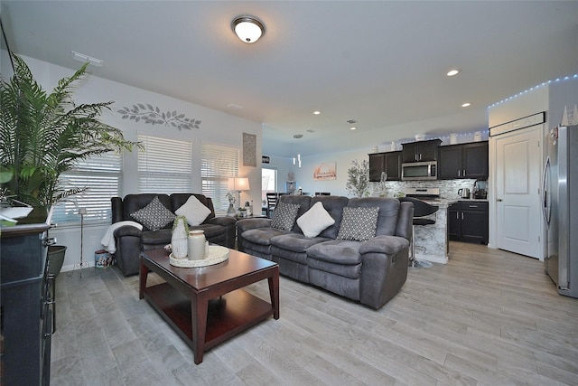 living room featuring a healthy amount of sunlight, visible vents, and light wood finished floors