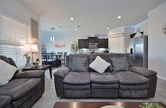 living area with baseboards, visible vents, and recessed lighting