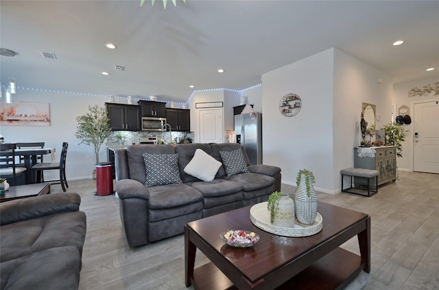 living room with baseboards, light wood-type flooring, visible vents, and recessed lighting