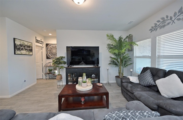 living area featuring visible vents, baseboards, and wood finished floors