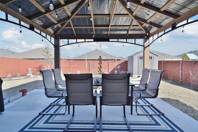 view of patio featuring a gazebo, a shed, an outdoor structure, and outdoor dining space