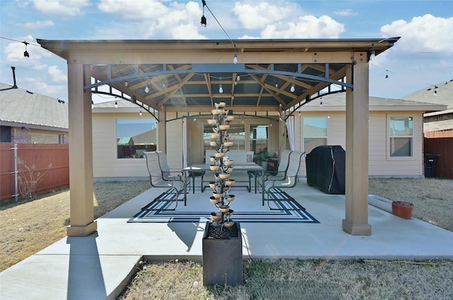 view of patio featuring a detached carport, fence, area for grilling, and a gazebo