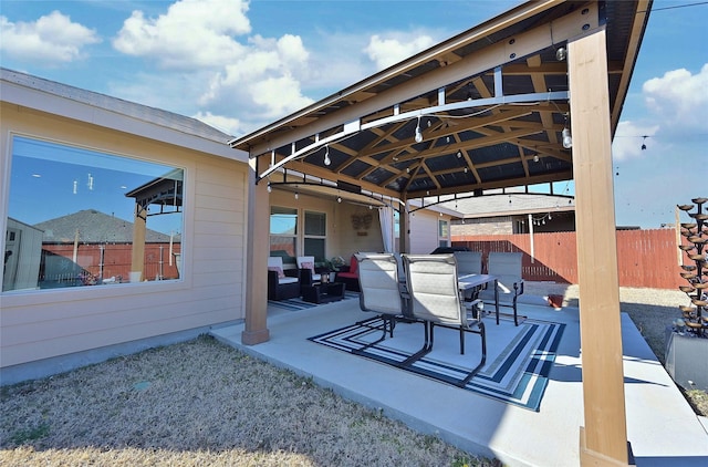 view of patio featuring fence, outdoor dining area, and a gazebo