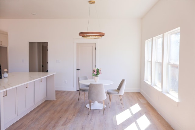 dining space featuring light wood-style flooring and baseboards