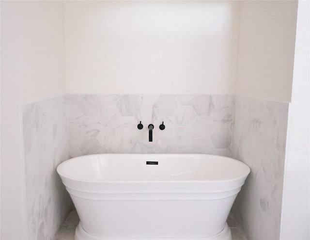 bathroom with a wainscoted wall, a soaking tub, and tile walls