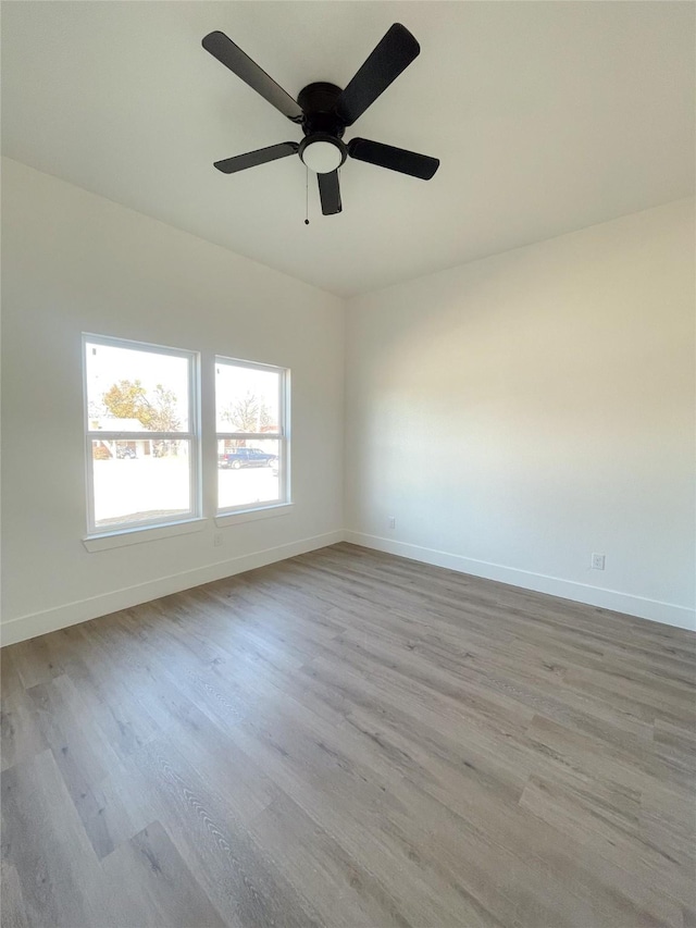 empty room featuring light wood-style floors, ceiling fan, and baseboards