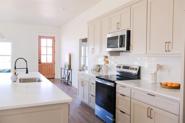 kitchen with tasteful backsplash, dark wood-type flooring, light stone countertops, stainless steel appliances, and a sink