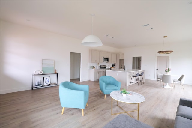 living room with visible vents, light wood-style flooring, and baseboards