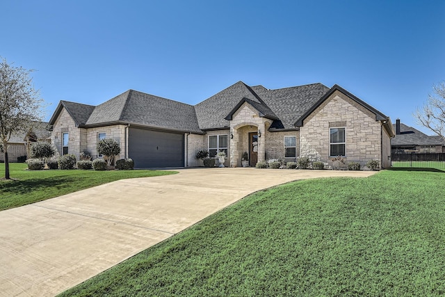 french country style house with a shingled roof, a front yard, driveway, and an attached garage