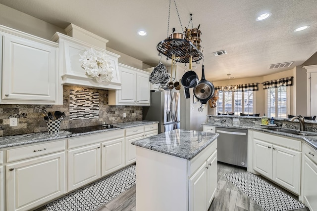 kitchen with stainless steel appliances, a sink, visible vents, and white cabinets