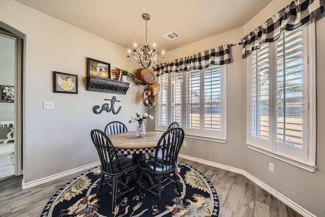 dining room featuring a chandelier, wood finished floors, visible vents, and baseboards