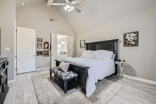 bedroom featuring baseboards, visible vents, ensuite bath, light wood-style floors, and high vaulted ceiling